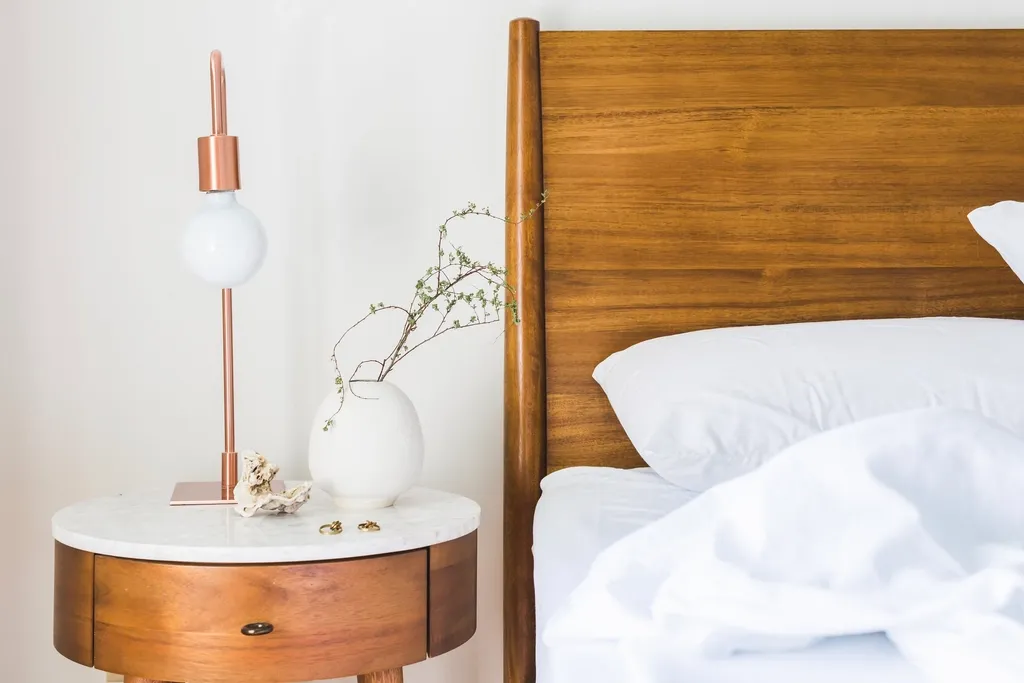 Houten nachtkastje naast een bed met teak hoofdbord